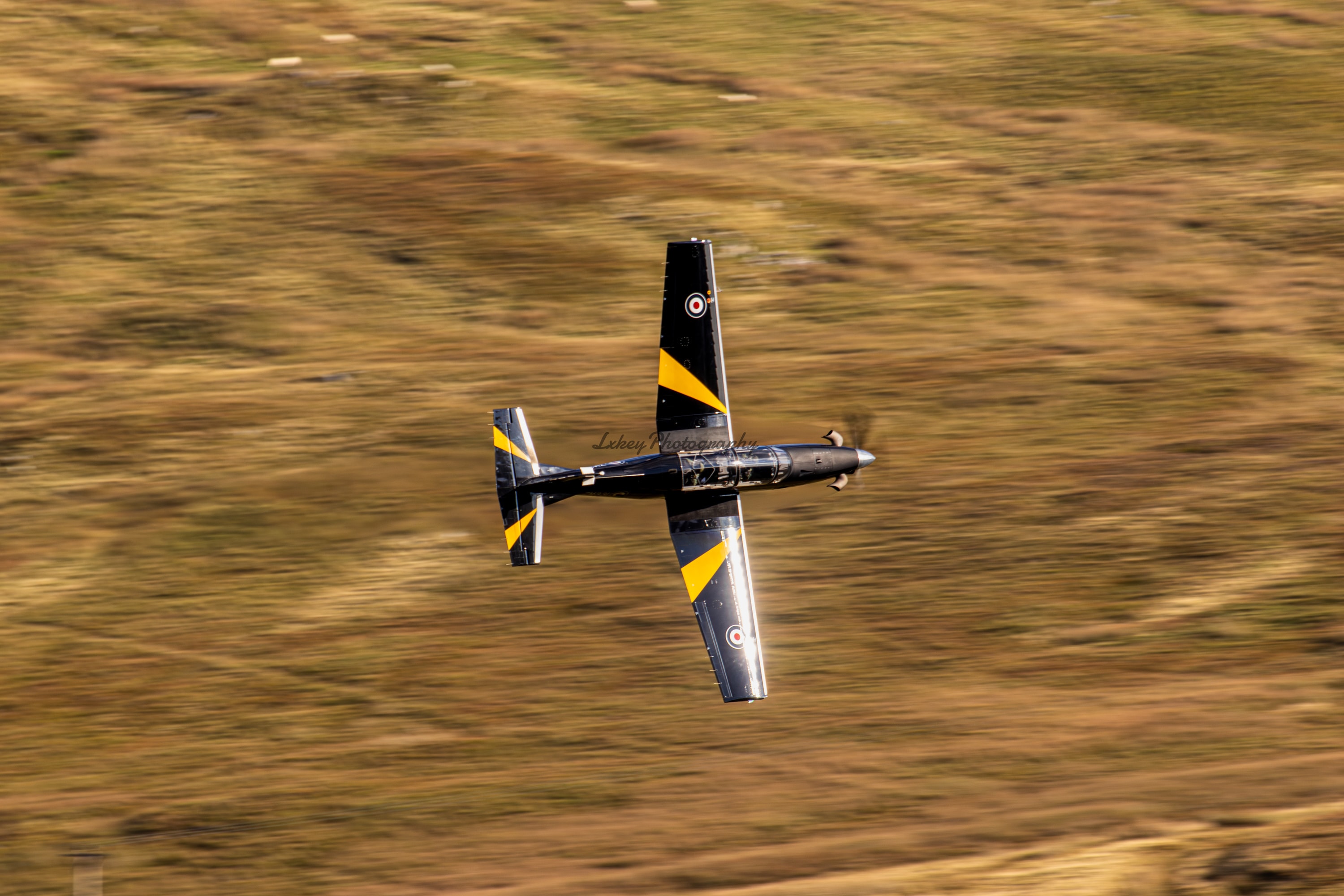 Aerobatic race aircraft flying knife edge over open country