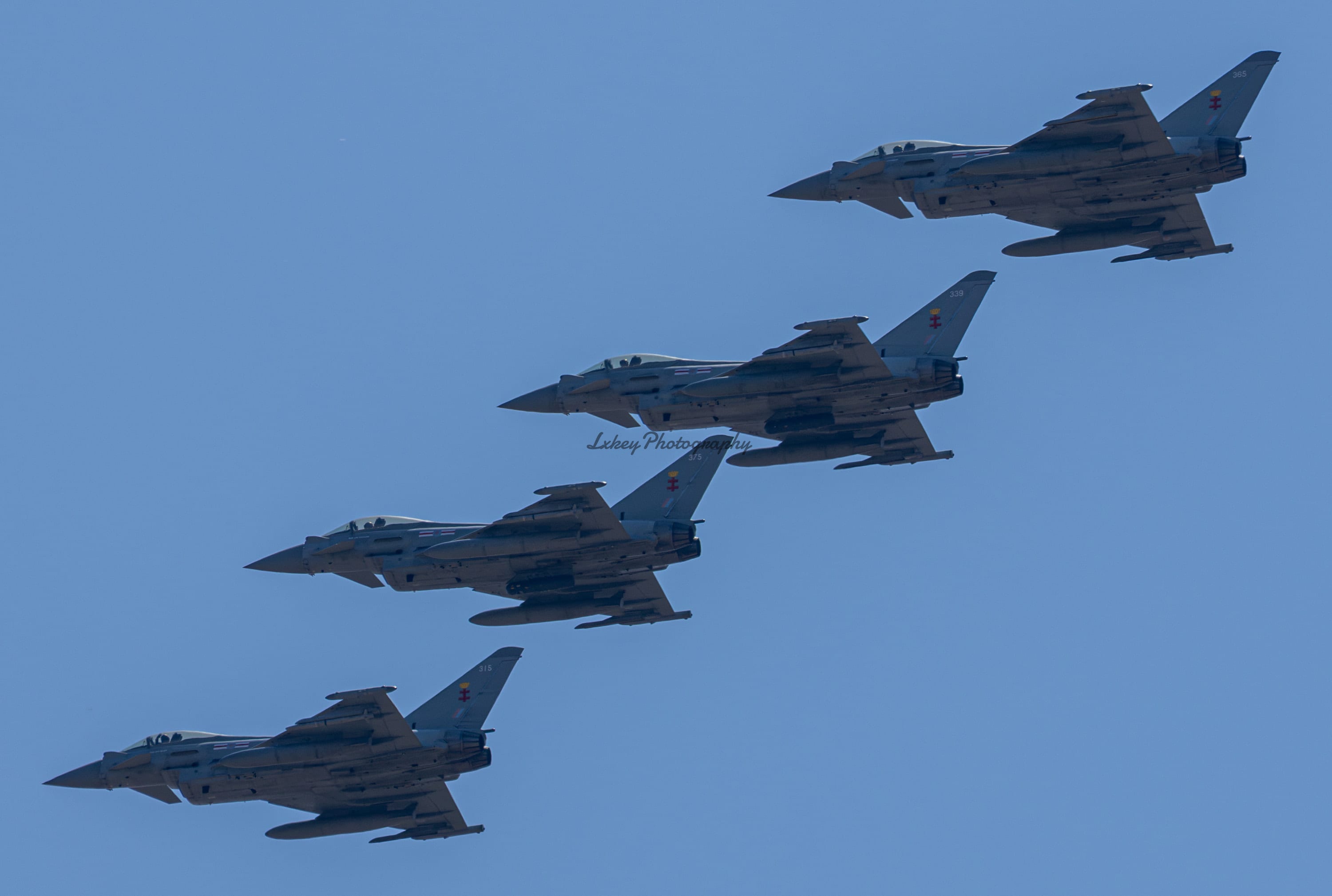 Four RAF Eurofighter Typhoons in echelon formation against clear blue sky